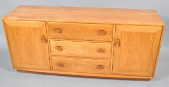 An Ercol elm sideboard with three central drawers, flanked by two cupboard doors,