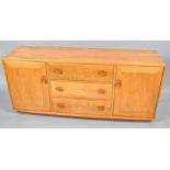 An Ercol elm sideboard with three central drawers, flanked by two cupboard doors,