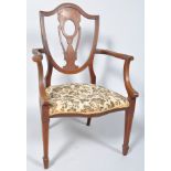 An Edwardian mahogany and marquetry elbow chair with shield shaped back on stuff over seat on