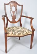 An Edwardian mahogany and marquetry elbow chair with shield shaped back on stuff over seat on