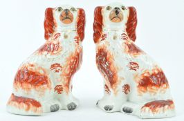 A pair of 19th century Staffordshire pottery figures of spaniels, picked out in iron red enamels,