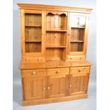A pine dresser, the upper section with glazed door cupboard, drawers and shelves,