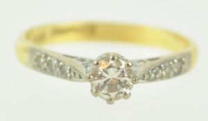 A yellow and white metal single stone ring.