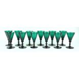 A group of twelve green glass wine glasses, circa 1800, with trumpet bowls over angular knops,