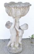 A reconstituted stone garden urn, the support modelled as two children,