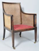 A Regency style bergere armchair, with upholstered seat, square tapering legs and brass casters,