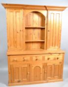 A two section pine dresser, the upper section with central shelf flanked by cupboard doors,