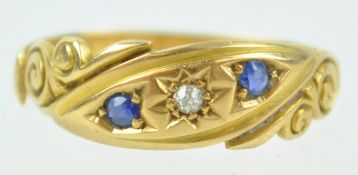 A yellow metal three stone ring set with sapphires and diamonds.