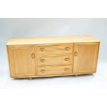 An Ercol elm sideboard, with two cupboard doors flanking the drawers,