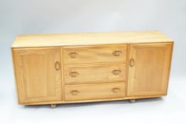 An Ercol elm sideboard, with two cupboard doors flanking the drawers,