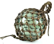 A large 19th century blown glass fishing float, in rope surround,