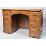 An oak kneehole desk with a central drawer flanked by four drawers to either side, on plinth base,