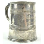 A silver mug, of tapering cylindrical form, with two bands of line engraving and a shaped handle,