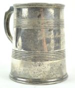 A silver mug, of tapering cylindrical form, with two bands of line engraving and a shaped handle,