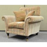 A Parker Knoll armchair with loose cushions on turned legs with brass casters,
