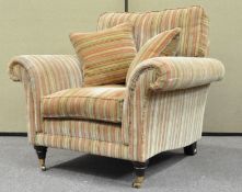 A Parker Knoll armchair with loose cushions on turned legs with brass casters,