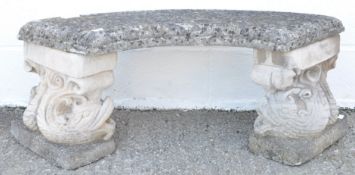 A reconstituted stone garden seat, on dolphin supports,