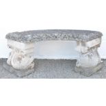 A reconstituted stone garden seat, on dolphin supports,