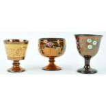 Three mid 19th century copper lustre pottery goblets, two painted with flowers, the largest 10.