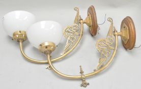 A pair of brass wall lights with opaque shades,