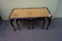 A nest of tables with leather tops with a small cabinet,