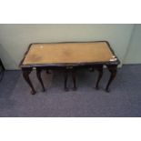A nest of tables with leather tops with a small cabinet,