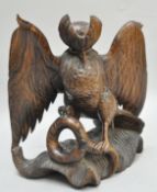 An Indonesian 1980's carved wooden figure depicting a bird of prey attacking a snake,