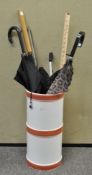 An Italian ceramic stick stand with a collection of umbrellas, a litter grab and other items,