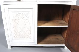 A white painted kitchen dresser with four shelves above two drawers above two carved cupboard doors,