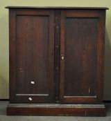 An oak cupboard, with two panel doors, raised on a plinth