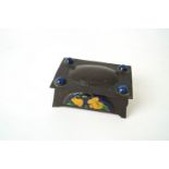 An Arts and Crafts copper box set with enamel panels decorated with flowers,