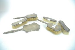 A silver four piece dressing table set and another clothes brush