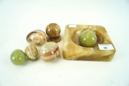 A shallow square marble bowl with onyx stand and five decorative onyx eggs