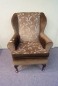 A 20th century fire side armchair on cabriole legs,