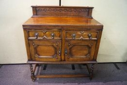 A small oak sideboard with two drawers above two cupboard doors