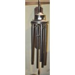 A large mixed metal wind chime on an oak back board