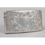 A silver card case of shaped rectangular form, profusely engraved with scrolling foliates