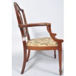 An Edwardian mahogany and marquetry elbow chair with shield shaped back on stuff over seat