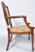 An Edwardian mahogany and marquetry elbow chair with shield shaped back on stuff over seat