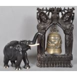 An Asian cast brass temple bell decorated with a running dragon on a carved ebony stand, 45cm high,