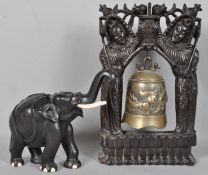 An Asian cast brass temple bell decorated with a running dragon on a carved ebony stand, 45cm high,