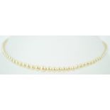 An 8mm white cultured pearl together with a single strand of graduated simulated pearls