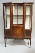 An Edwardian mahogany display cabinet with concave central glazed panel