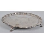 A small silver salver with shaped edge raised on four plain legs, Chester 1908, 20cm diameter
