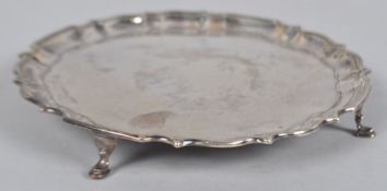 A small silver salver with shaped edge raised on four plain legs, Chester 1908, 20cm diameter