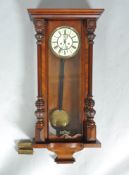 A mahogany cased Vienna style wall clock with two applied turned columns and a crop base
