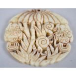 A pale jade circular carved pendant carved with frogs below palm trees and foliage.