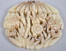 A pale jade circular carved pendant carved with frogs below palm trees and foliage.