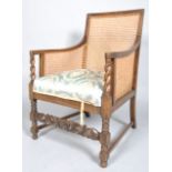 An oak bergere, with barley twist arms, with a foliate and flowerhead carved front stretcher,