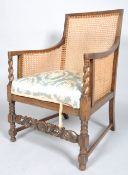 An oak bergere, with barley twist arms, with a foliate and flowerhead carved front stretcher,